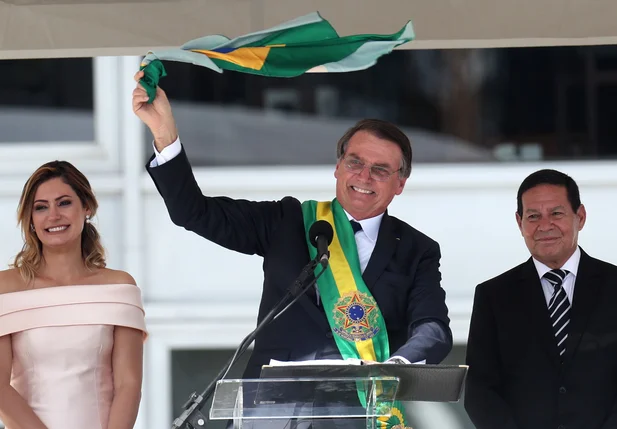 Bolsonaro segura bandeira do Brasil após receber a faixa presidencial