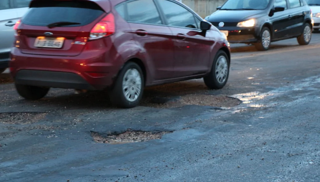 Carros têm dificuldade de passar pelos buracos