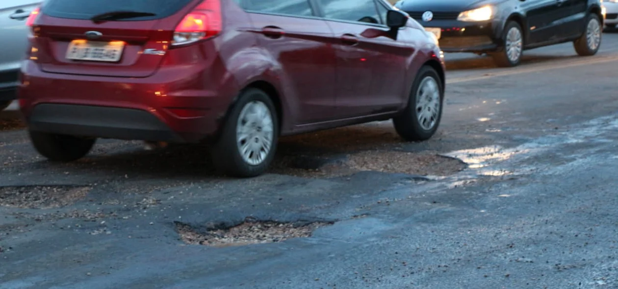 Carros têm dificuldade de passar pelos buracos