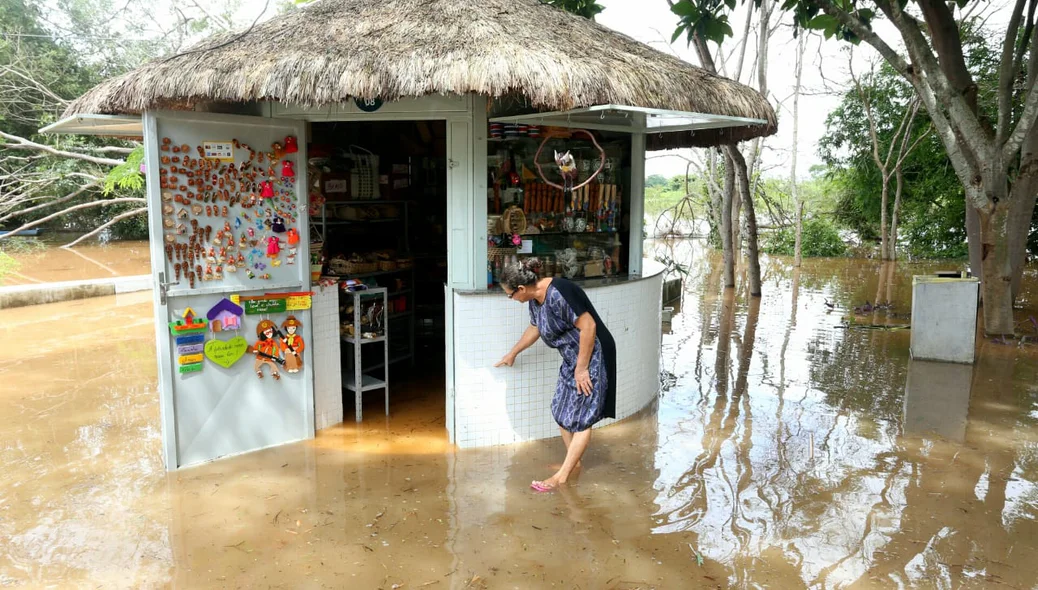 Dona lúcia mostrando onde chegou o nível da água