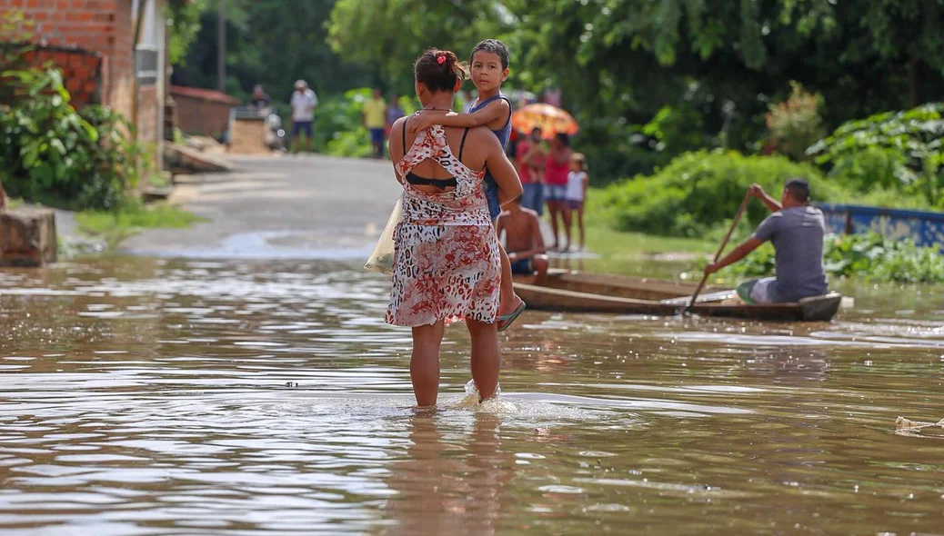 Mãe e filha atravessam rua alagada no bairro Água Mineral