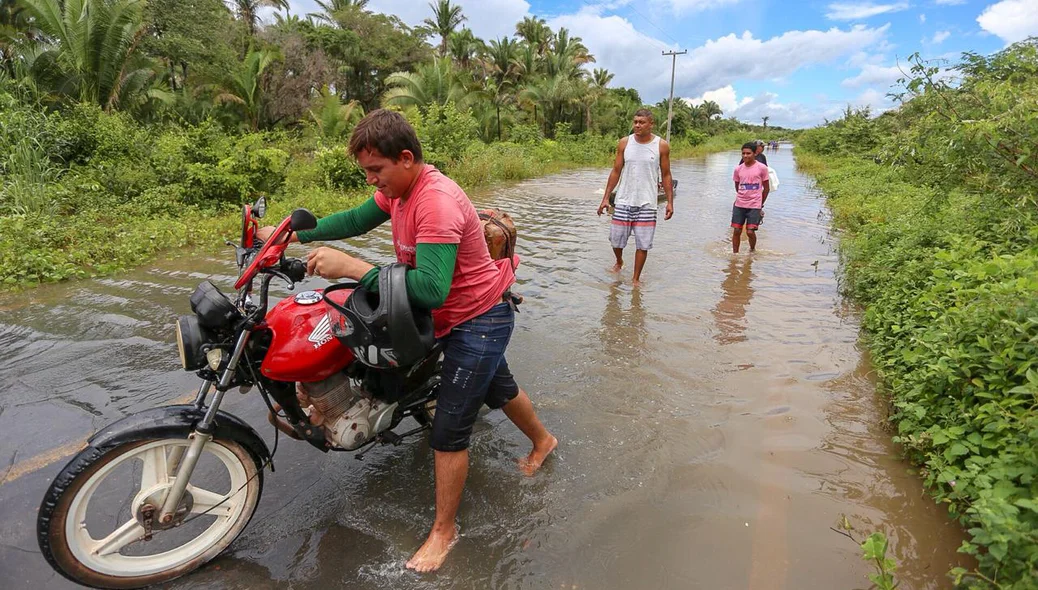 Populares tiram água de região alagada 