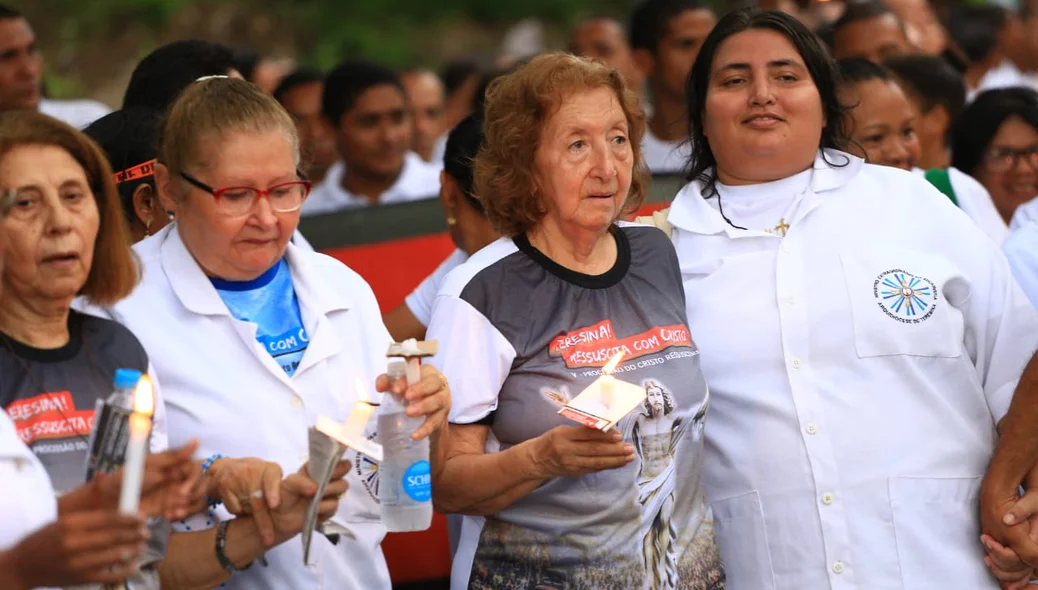 Fiéis acendem velas e caminham durante procissão 