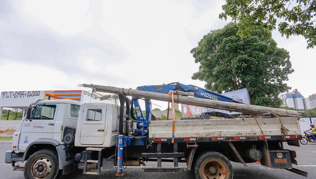 Caminhão recolhendo poste danificado