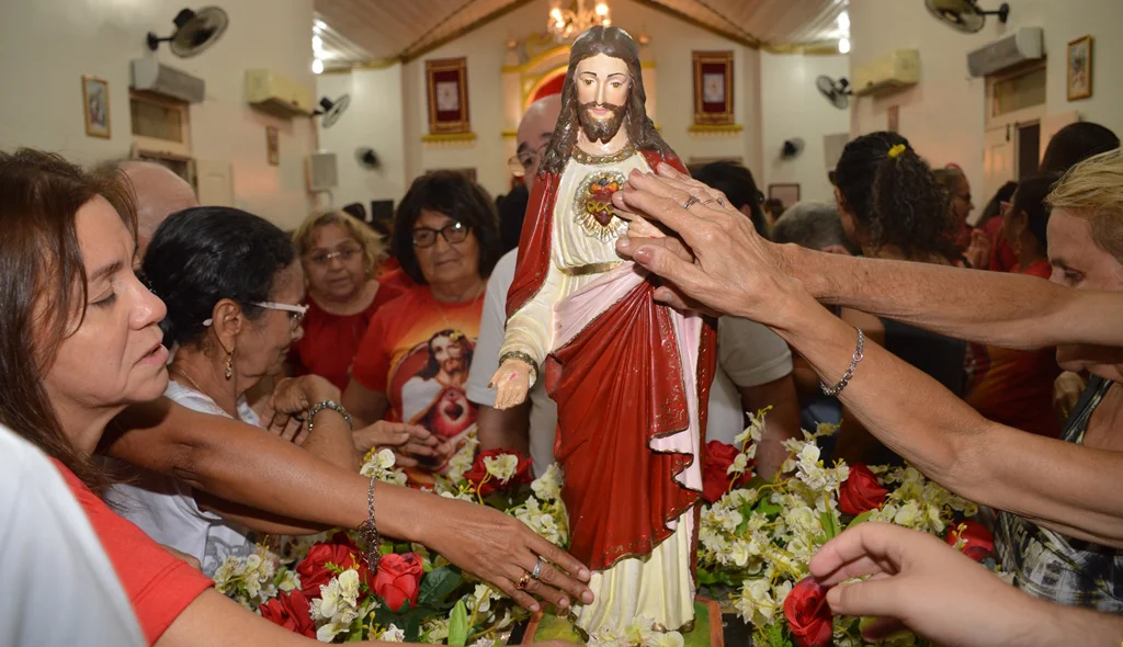 Devotos tocam a imagem do Sagrado Coração de Jesus