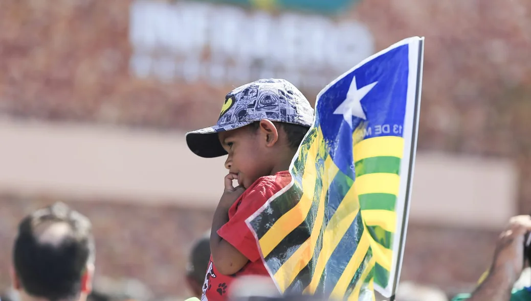 Menino segura a bandeira do Piauí enquanto espera a visita do presidente Bolsonaro a Parnaíba