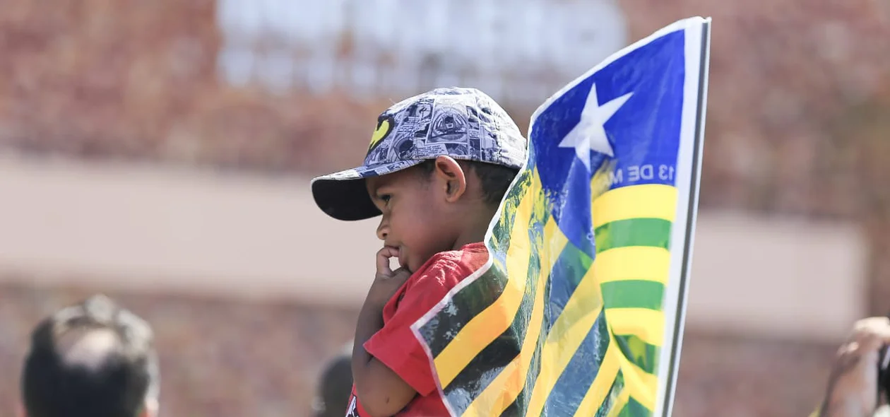 Menino segura a bandeira do Piauí enquanto espera a visita do presidente Bolsonaro a Parnaíba