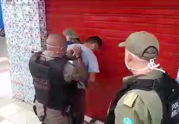 Comerciante sendo algemado pela PM