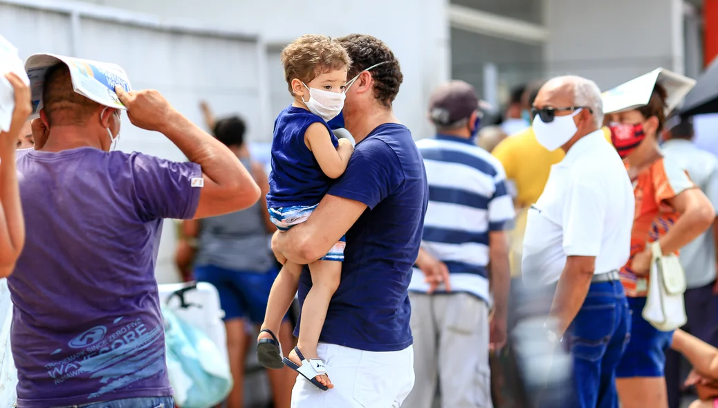 Pai com criança de colo na fila do banco
