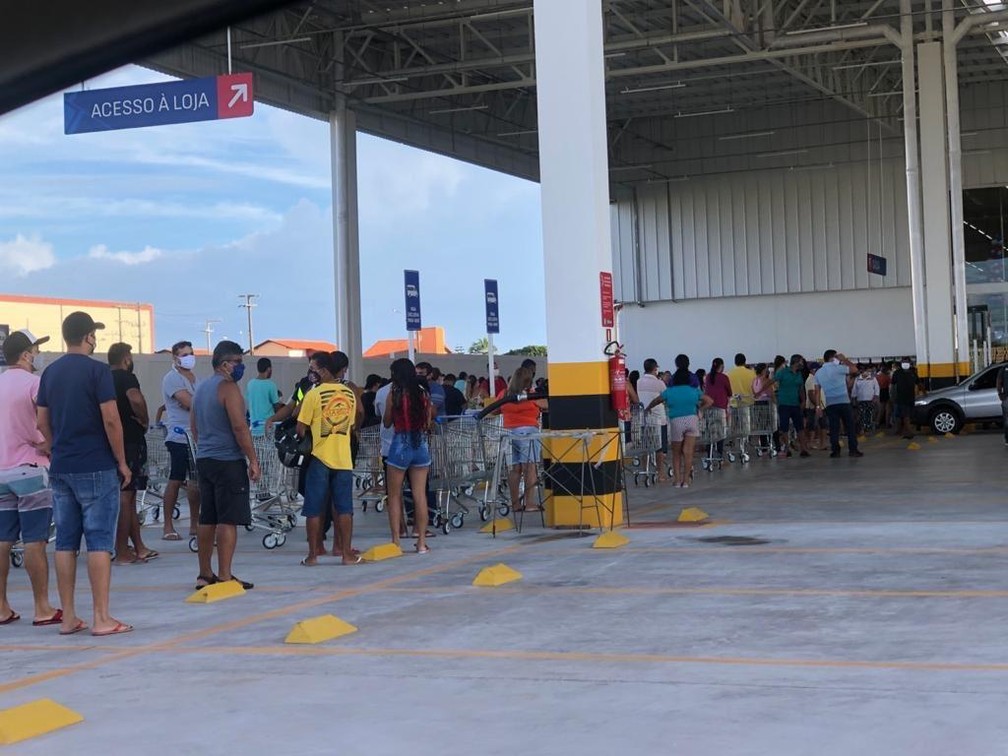 Dezenas de pessoas aguardam no lado externo do supermercado
