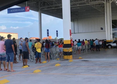 Dezenas de pessoas aguardam no lado externo do supermercado