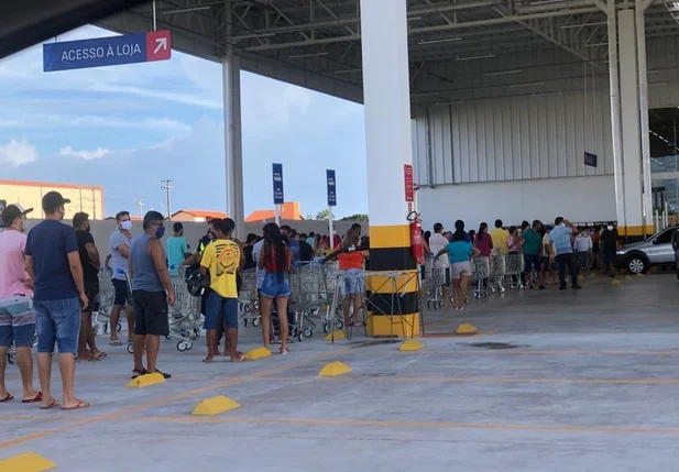 Dezenas de pessoas aguardam no lado externo do supermercado