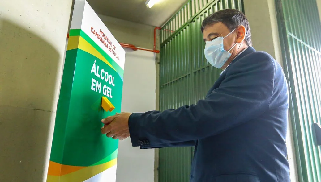 Wellington Dias passa gel na mão na entrada do hospital