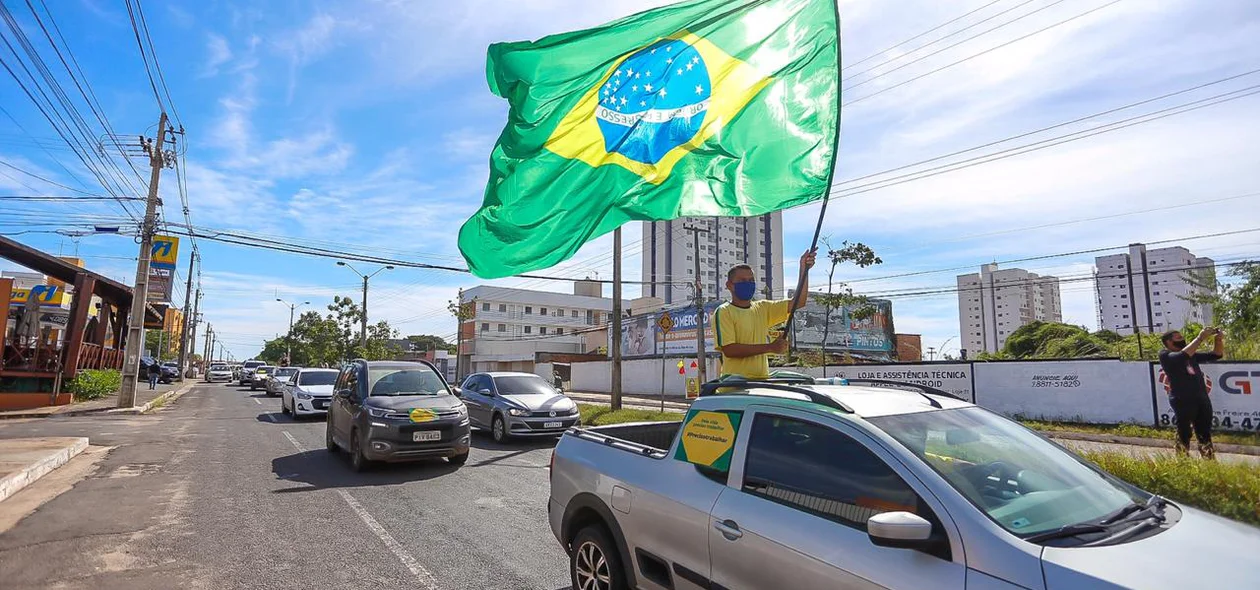 Empresário segurando bandeira do Brasil durante carreata