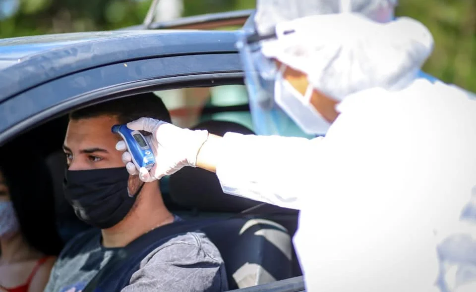 Agente de saúde medindo temperatura de motorista