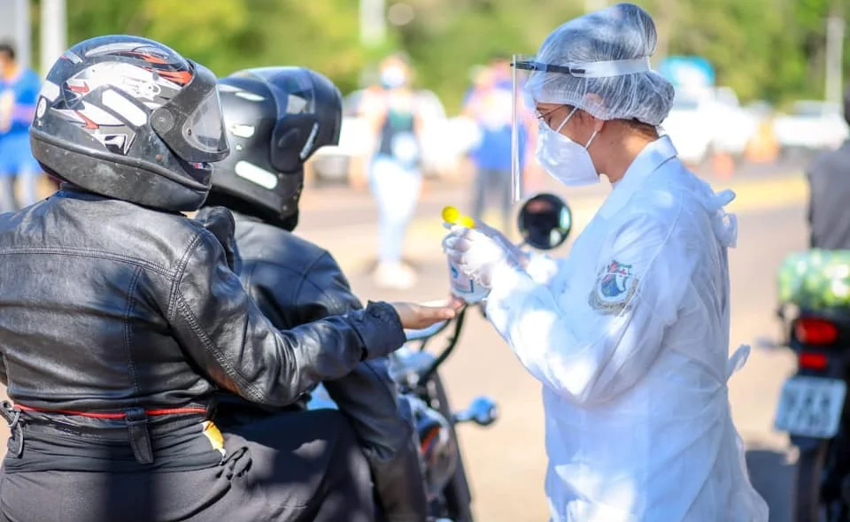 Motoqueiros sendo higienizados com álcool gel