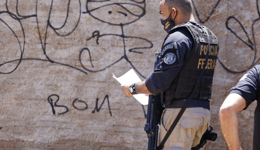 Agente da PF de posse do mandado de busca e apreensão