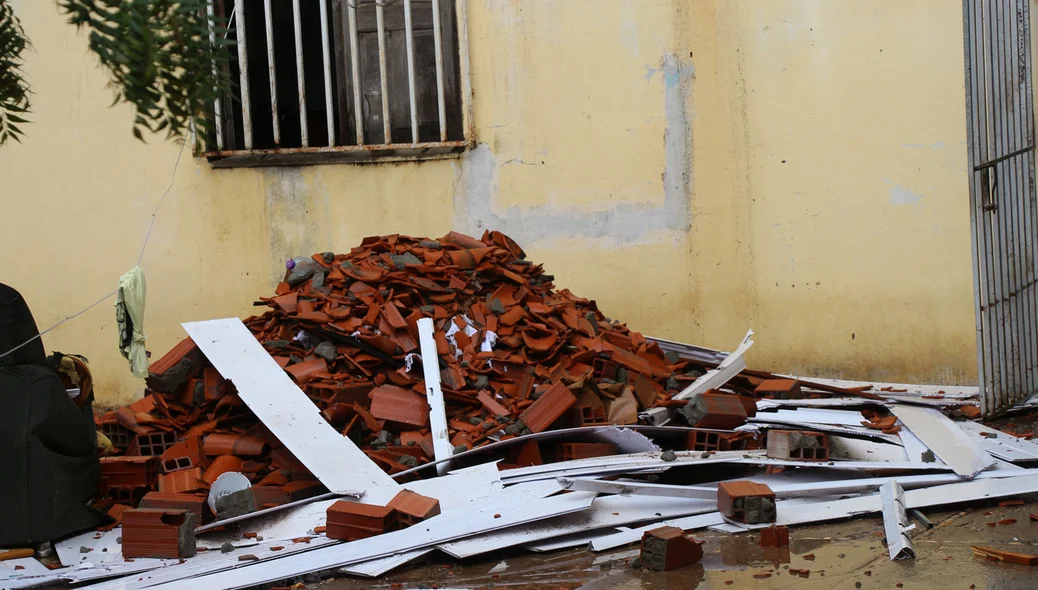 Moradores retiram restos do telhado de dentro da casa