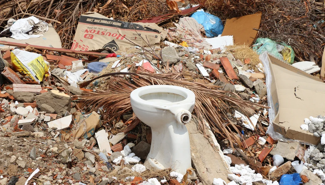 Aparelho sanitário e outros objetos jogados no terreno
