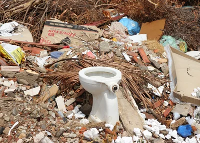 Aparelho sanitário e outros objetos jogados no terreno