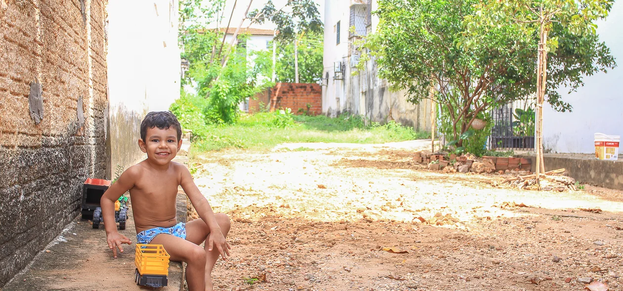 Criança brincando na porta de casa sem calçamento
